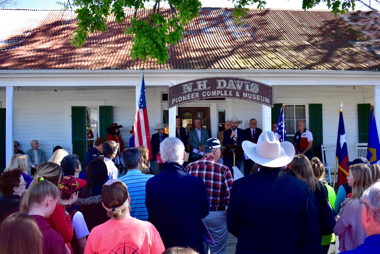 Crowd listening to the history of the Lake Creek Settlement in front of the Nat Hart Davis Cottage.
